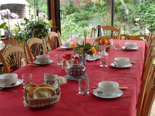 une table avec un tissu de table rouge et de la nourriture dans l'établissement Chambre d'Hôtes Broualeuc, à Saint-Potan