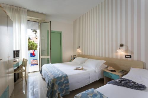 A bed or beds in a room at Hotel Calypso- Rimini Marina Centro