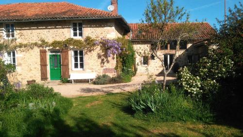 an old stone house with a green door and flowers at Les Trois Chenes in Videix