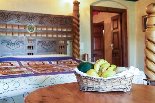 a basket of fruit on a table in front of a bed at Chateau Garli in Garli
