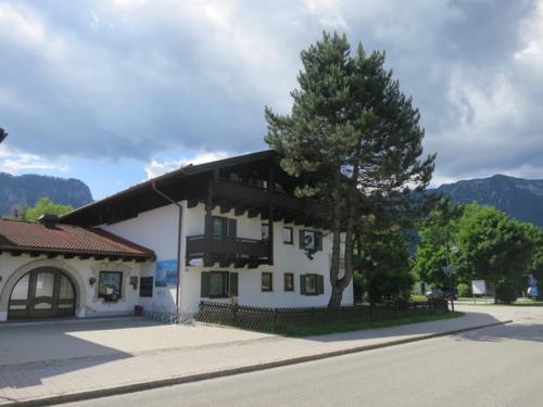 a white building with a tree next to a street at Studio App. 337 mit Blick auf die Berge in Inzell