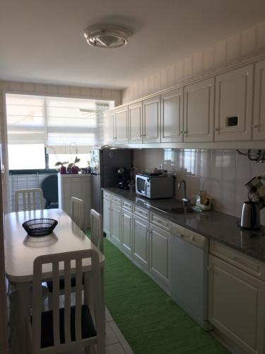 a kitchen with white cabinets and a green floor at Casa na Praia in Póvoa de Varzim
