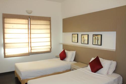 two beds in a room with two windows at AMC Comforts in Bangalore