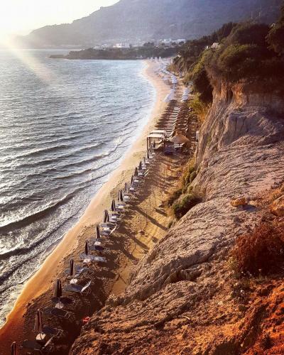 a beach with chairs and umbrellas and the ocean at Villa Amor in Pefki Rhodes