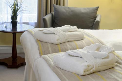 two towels are sitting on a bed with a table at Best Western Plus Dunfermline Crossford Keavil House Hotel in Dunfermline
