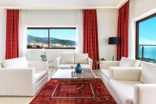 a living room with white furniture and red curtains at BURJ ON BAY Hotel in Jounieh