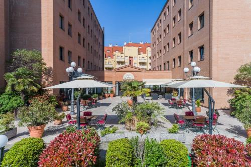 a courtyard with tables and chairs and umbrellas at Hotel Michelangelo in Sassuolo