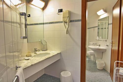een badkamer met een wastafel, een toilet en een spiegel bij Hotel Meripol in Alba Adriatica