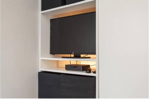 a flat screen tv on a shelf with a television at Shirley Apartments, Cozy Studio, Self Check in, 10 min Drive to City Centre, Walking to Redbridge Train Station in Southampton