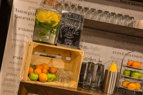 a shelf with a container of fruit and a drink at Postillion Hotel Deventer in Deventer
