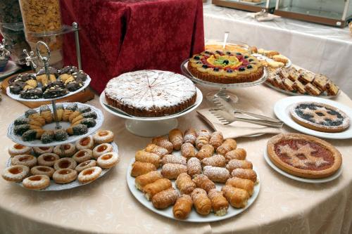 a table with many different types of pastries and pies at Hotel Excelsior in Monfalcone