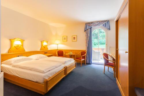 a bedroom with a bed and a table and a window at Hotel Erbprinzenpalais in Wernigerode