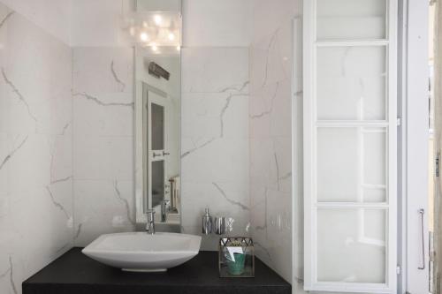 a white bathroom with a sink and a mirror at Caffè dell'Arte Boutique Rooms Locarno in Locarno