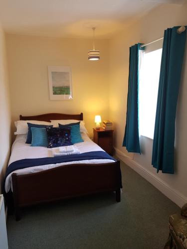 a bedroom with a bed with blue curtains and a window at Bridge House in Carrick on Shannon