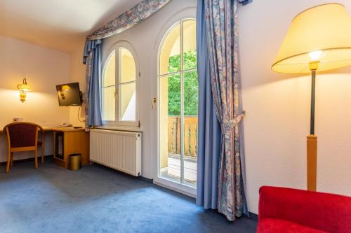 a room with a large window and a desk and a table at Hotel Erbprinzenpalais in Wernigerode