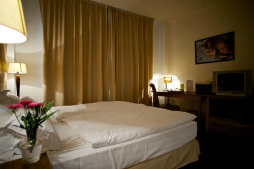 a hotel room with a bed and a desk with a television at Rembrandt Old Town in Bucharest
