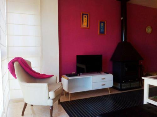 ein Wohnzimmer mit einem weißen Stuhl und einem TV in der Unterkunft Apartamento Belobodia in Cáceres