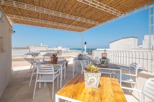 um pátio com mesas e cadeiras e o oceano em Palazzo Maringelli em Polignano a Mare