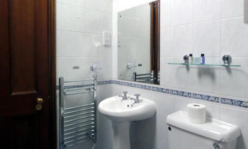 a bathroom with a sink and a toilet and a mirror at Macdonald Elmers Court Resort in Lymington
