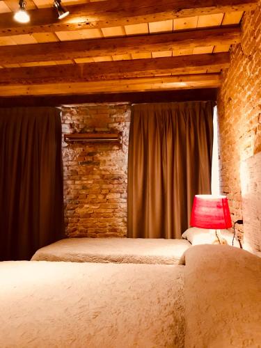 a bedroom with two beds and a brick wall at Barbara’s rooms in Chioggia