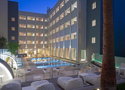 un hotel con piscina frente a un edificio en Melrose Rethymno by Mage Hotels, en Rethymno