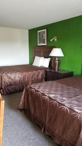 2 Betten in einem Hotelzimmer mit grünen Wänden in der Unterkunft Island Inn in Grand Island