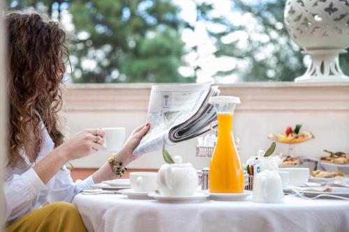 a woman sitting at a table reading a newspaper at Relais Villa San Martino in Martina Franca