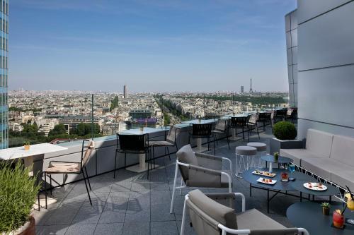 a rooftop patio with tables and chairs on a building at Melia Paris La Defense in Courbevoie