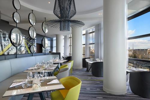 a restaurant with tables and chairs and large windows at Melia Paris La Defense in Courbevoie