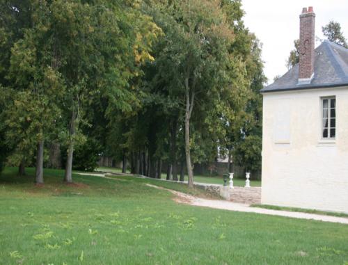 a white building in a grassy field with trees at Château de Maudetour in Maudétour-en-Vexin