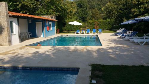 ein Swimmingpool mit Liegestühlen und Sonnenschirm in der Unterkunft Casa do Contador T3 / T6 in Vieira do Minho