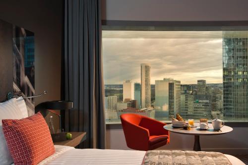 a hotel room with a bed and a table and a window at Melia Paris La Defense in Courbevoie