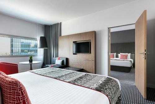 a hotel room with a large bed and a tv at Melia Paris La Defense in Courbevoie