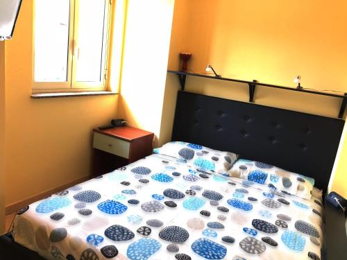 a bedroom with a bed with a blue and white comforter at Luna in Fondachello