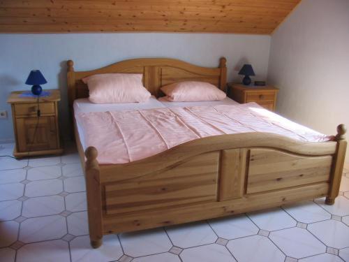 a wooden bed in a bedroom with two night stands at Panorama Gasthof Stemler in Eulenbis