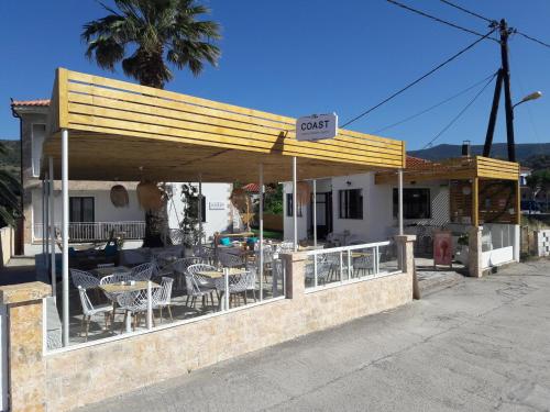 a restaurant with tables and chairs under a roof at The Coast seaside rooms in Anaxos