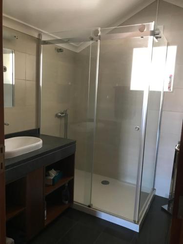 Un baño con ducha de cristal y lavabo. en Silveira by the Sea, en Angra do Heroísmo