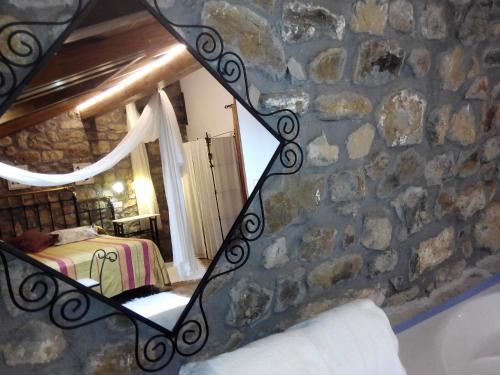 a mirror in a room with a rock wall at Posada Montero de la Concha in Esles