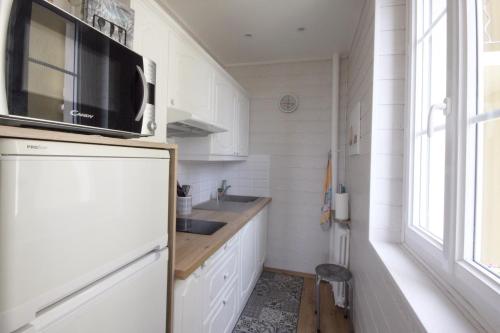 a kitchen with a refrigerator with a microwave above it at Le quai Sud in Fécamp