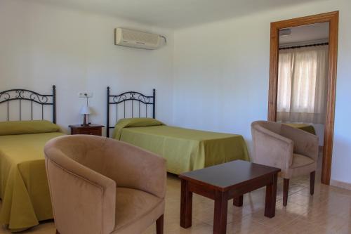 a bedroom with two beds and a table and chairs at Hostal Esperanza in Benajarafe