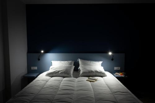 a large bed in a dark room with two pillows at Atao Residence- Rennes Sud in Vern-sur-Seiche