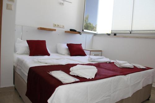 a bed with white sheets and red pillows on it at AELBİSTAN OTEL in Didim