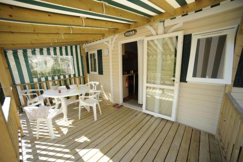 een houten terras met een tafel en stoelen erop bij ULVF La Grande Dune in Saint-Hilaire-de-Riez