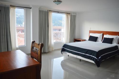 a bedroom with a bed and a desk and windows at COLOMBIA-Hotel Hontibon in Pamplona