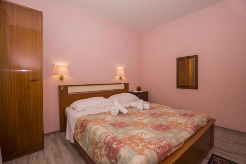 a bedroom with a bed with two pillows on it at Apartments & Rooms Ribarić in Lovran