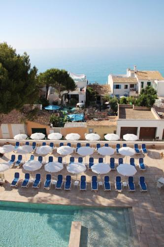 a group of chairs and umbrellas next to a swimming pool at Hotel Clumba in Cala Ratjada