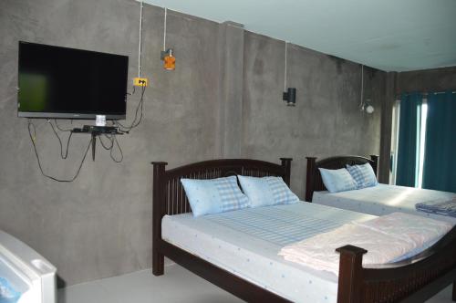 a bedroom with two beds and a flat screen tv at BaanSunlomjoy in Chom Thong