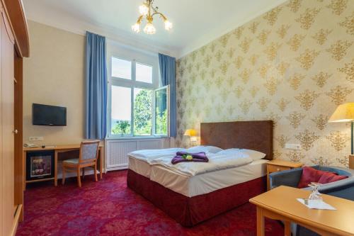 a hotel room with a bed and a desk and a window at Hotel Erbprinzenpalais in Wernigerode