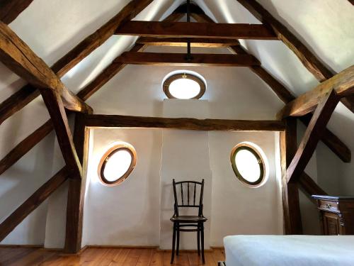 a room with a chair and two round windows at The Houses of History - anno 1830 in Tihany