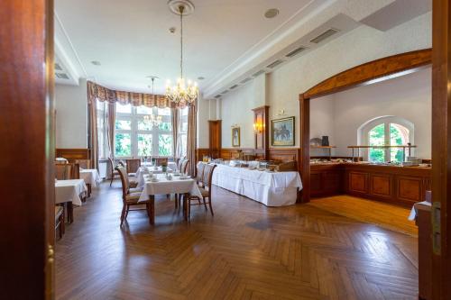a dining room with tables and chairs and a chandelier at Hotel Erbprinzenpalais in Wernigerode